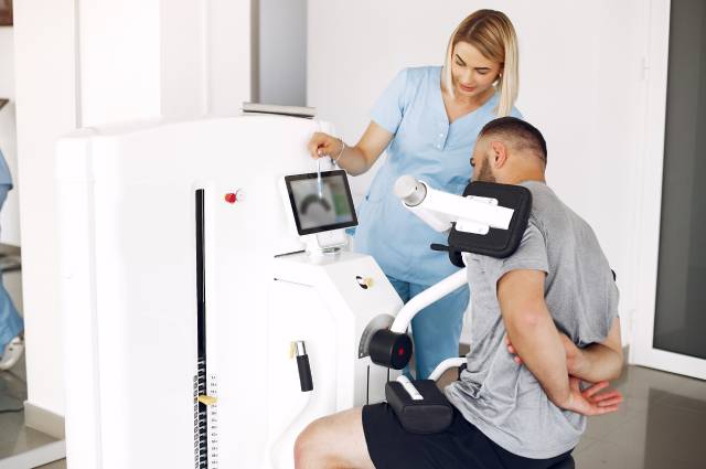 Paciente y fisioterapeuta usando tecnología en fisioterapia.
